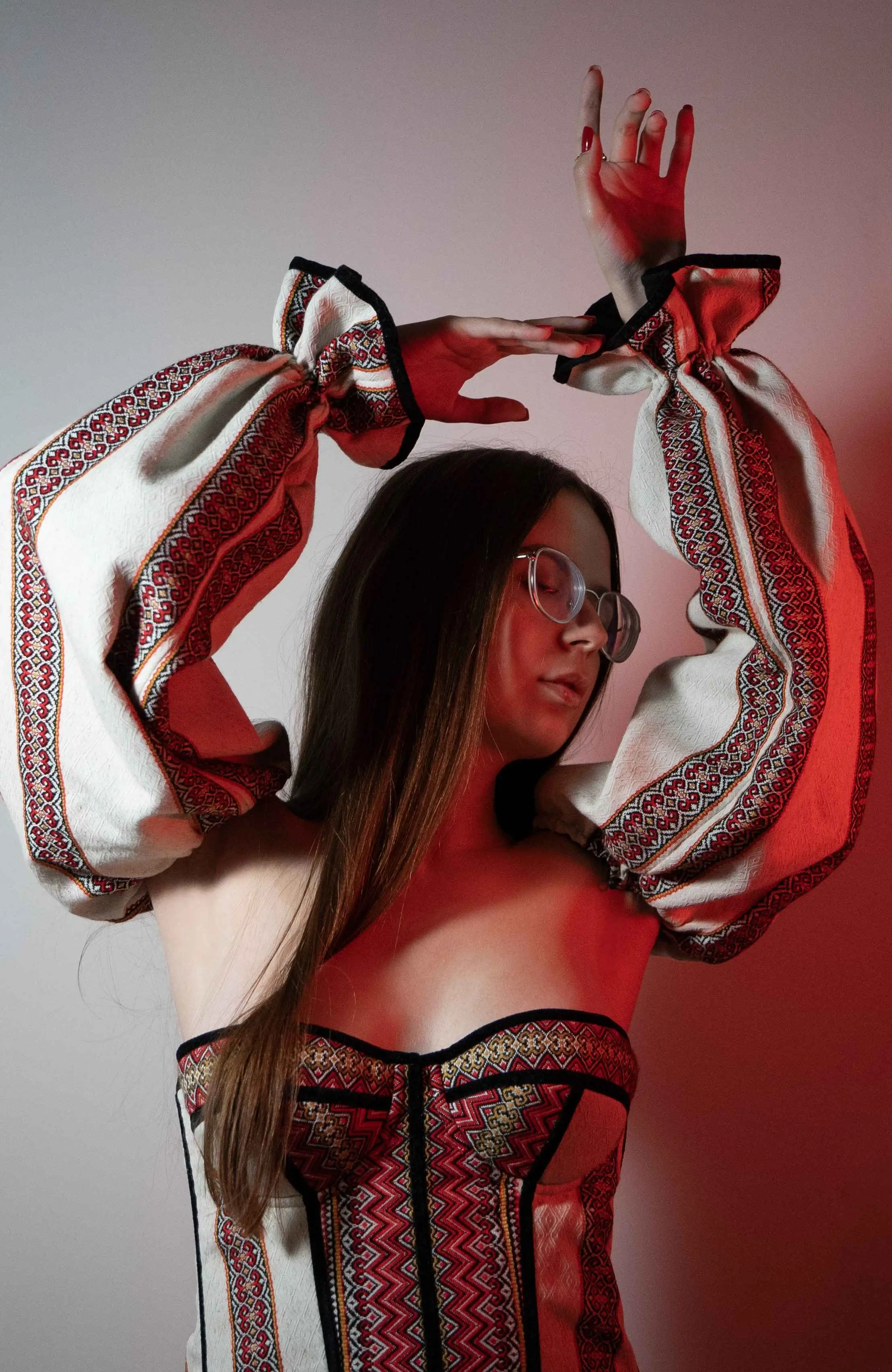 Girl with her hands on top on white and red background wearing folk clothes